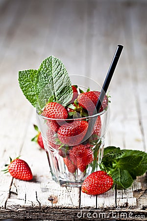 Organic red strawberries glass and mint leaves on rustic wooden background Stock Photo