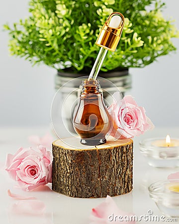 Organic rose serum on wooden podium, rose petals and candles Stock Photo