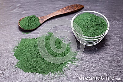Organic spirulina algae powder on black slate platter background Stock Photo