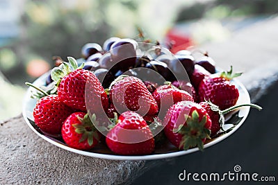 Organic sweet cherry and strawberry on a white plate. Stock Photo