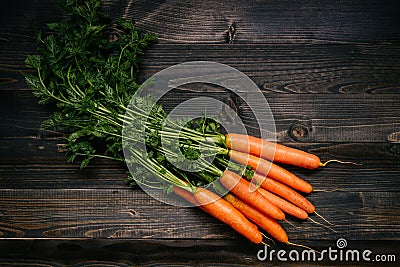 Organic vegetables. Fresh harvested carrots on the dark wooden background, top view Stock Photo