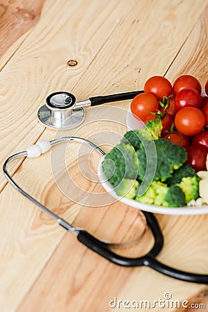 Organic vegetables on plate near stethoscope on wooden surface Stock Photo