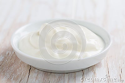 Organic white Greek yogurt or sour cream in bowl on white wooden background Stock Photo