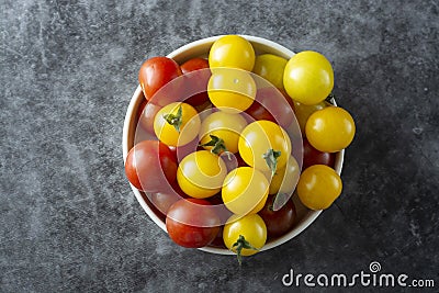 Yellow and red tomatoes in plate, isolated over dark background Stock Photo