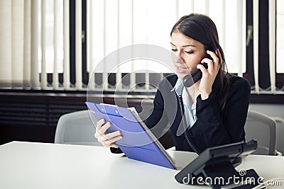 Organized responsible office worker business woman giving instructions via phone call. Looking confused checking notes and paperwo Stock Photo