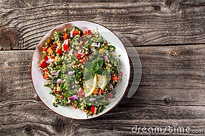 Oriental tabbouleh salad with couscous, vegetables and herbs in a brown bowl on wooden background. banner, catering menu recipe Stock Photo