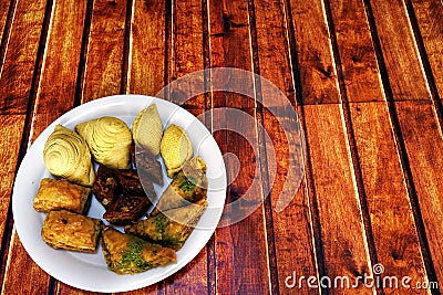 Oriental, Turkish, Azerbaijani baklava sweets in a white plate on a brown wooden table, copy space Stock Photo