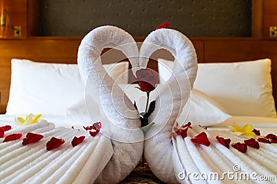 Origami swans made out of towels and laid out on a bed in a honeymoon suite Stock Photo