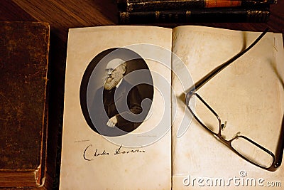 The origin of species by Charles Darwin opened on first page with glasses on the second page. Stock Photo