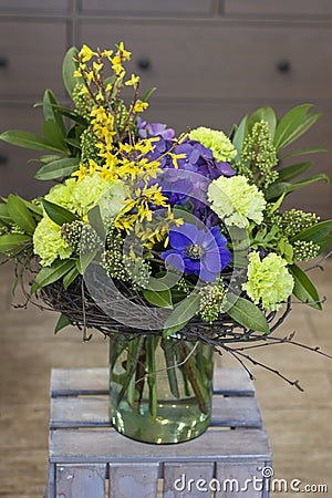 The original bouquet of blue anemones, carnations, forsythia stands in a glass vase Stock Photo