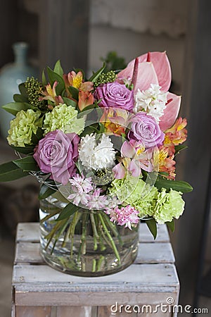 The original bouquet of flowers standing on a wooden box in the room Stock Photo