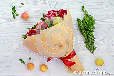 Original bouquet of fruits and flowers lies on a wooden table Stock Photo