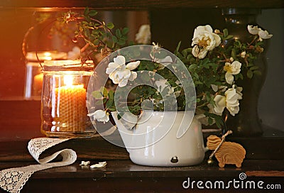 An original still life of Russia with the fire of a wax candle. A rustic still life with white flowers and a burning candle, a sti Stock Photo