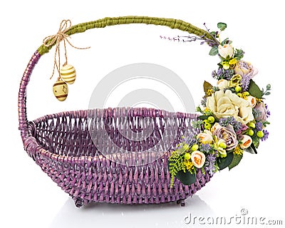 Original wicker basket of purple for Easter. Floral decor in olive tones with beige flowers, greens and hanging decorative eggs Stock Photo