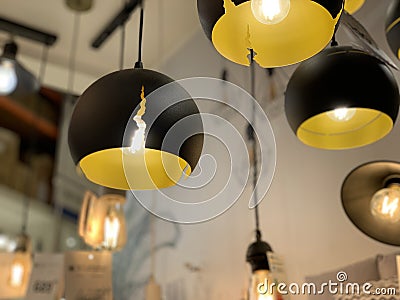 Original yellow-black ceiling lights. Modern chandeliers in the electrical goods store. Pendant floor lamps for interior Stock Photo