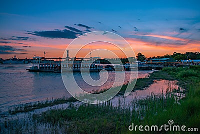 Beautiful panoramic view of Grand Floridian Resort & Spa, green forest and Magic Kingdom wharf on colorful sunset background at Wa Editorial Stock Photo