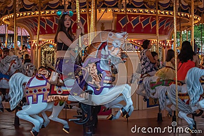 Woman enjoying Prince Charming Regal Carrousel in Magic Kingdom at Walt Disney World . Editorial Stock Photo