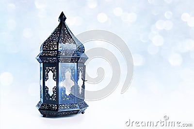 Ornamental dark Moroccan, Arabic lantern on the table. Burning candle, glittering bokeh lights stars. Greeting card for Stock Photo