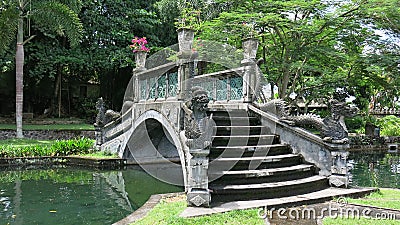 Ornamental stone bridge over water canal in royal garden. Historic building with elements of Balinese culture. Stock Photo