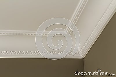 Ornamental white molding decor on ceiling of white room close-up detail. Interior renovation and construction concept. Stock Photo