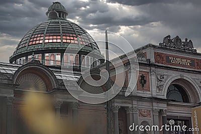 Ornate domed building surrounded by another large building under a cloudy sky in Copenhagen Editorial Stock Photo