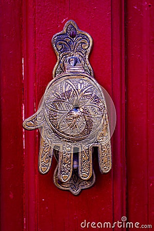 Hand of Fatima, a typical Moroccan design, as a door knocker on a red wooden front door Stock Photo