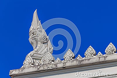 Ornate naga statue on the ornamented tiered ubosot roof of Wat Kaew Korawaram white buddhist temple in Krabi, Thailand Stock Photo