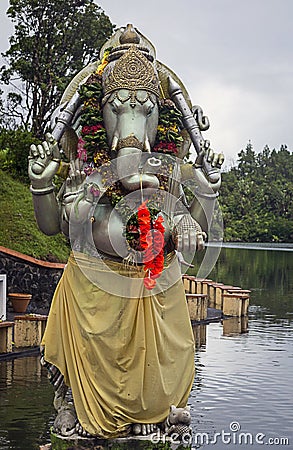 An ornate statue of an Indian god standing on the shore of a lake Stock Photo