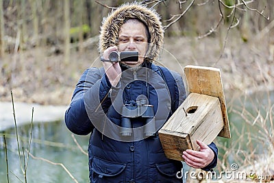 Ornithologist with camcorder and bird cage near river Stock Photo