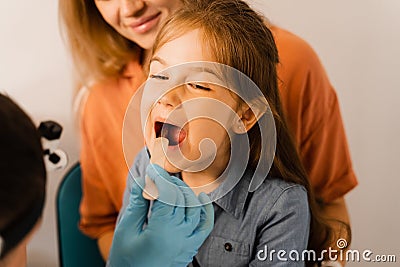 Oropharyngoscopy procedure for child. Otolaryngologist examines child throat with spatula. Family consultation with Stock Photo