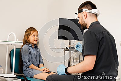 Oropharyngoscopy procedure. Otolaryngologist examines child throat with spatula. Consultation with laryngologist. Stock Photo