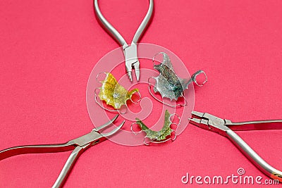 Orthodontic metal tools and dental braces or retainers, pink background Stock Photo