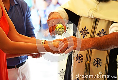 Orthodox christening icon - priest puts baptism oil on the hand of godmother Stock Photo