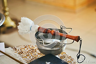 Orthodox priest holds a bible on a table with various objects needed for baptism Stock Photo