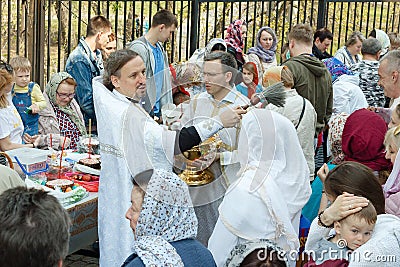 Orthodox priest sprinkles Christians with Holy water and illuminates the traditional. Religious holiday. Religious holiday in Russ Editorial Stock Photo