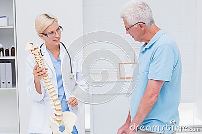 Orthopedic doctor explaining anatomical spine to senior man Stock Photo