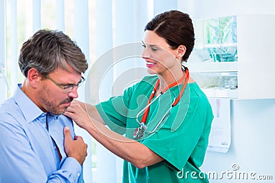 Orthopedist examining shoulder of patient in surgery Stock Photo