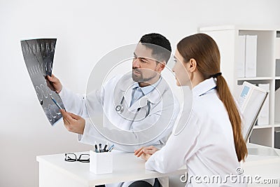 Orthopedists examining X-ray picture at desk in clinic Stock Photo