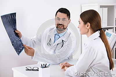 Orthopedists examining X-ray picture at desk in clinic Stock Photo