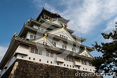 Osaka Castle majestic main tower with green traditional roofs and gold cravings, seen from below, Osaka, Japan. Stock Photo