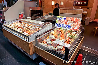 Lot of burned king crab legs and prawn in a small seafood freezer display Editorial Stock Photo