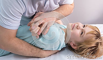 An osteopath works with the child. Work with the chest, shoulders and spine. There is a teenage child on the couch Stock Photo