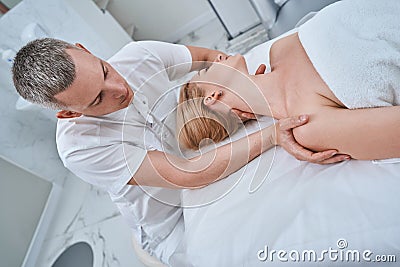 Osteopathic physician treating a young woman for cervicalgia Stock Photo