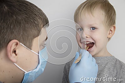 An otolaryngologist examines a child`s throat with a wooden spatula. A possible diagnosis is inflammation of the pharynx, tonsils Stock Photo