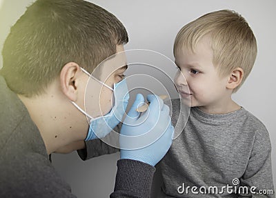 An otolaryngologist examines a child`s throat with a wooden spatula. A possible diagnosis is inflammation of the pharynx, tonsils Stock Photo