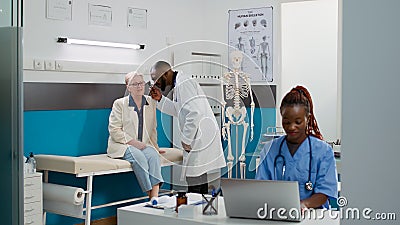 Otologist doing ear examination with otoscope on old patient Stock Photo