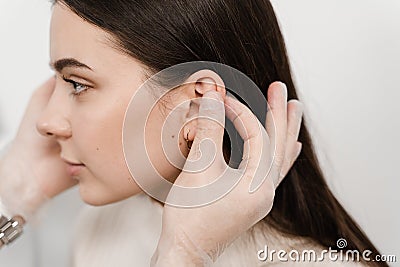 Otoplasty ear surgery. Surgeon doctor examines girl ears before otoplasty cosmetic surgery. Otoplasty surgical reshaping Stock Photo