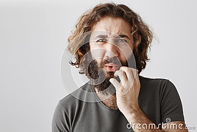 Ouch, it must hurt. Studio shot of worried eastern male show empathy and frowning, holding hand near folded lips, seeing Stock Photo