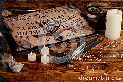 Ouija Board with candles. Seance on wooden table. The mystical atmosphere of the call of spirits. Black magic Stock Photo
