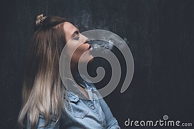 Oung blonde girl smokes electronic cigarette Stock Photo